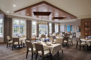 A gourmet dining room with white table linens within a senior living community