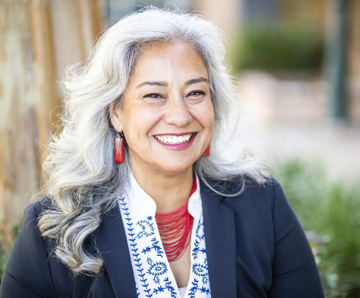 Close up shot of a smiling senior woman with long hair and bold jewelry