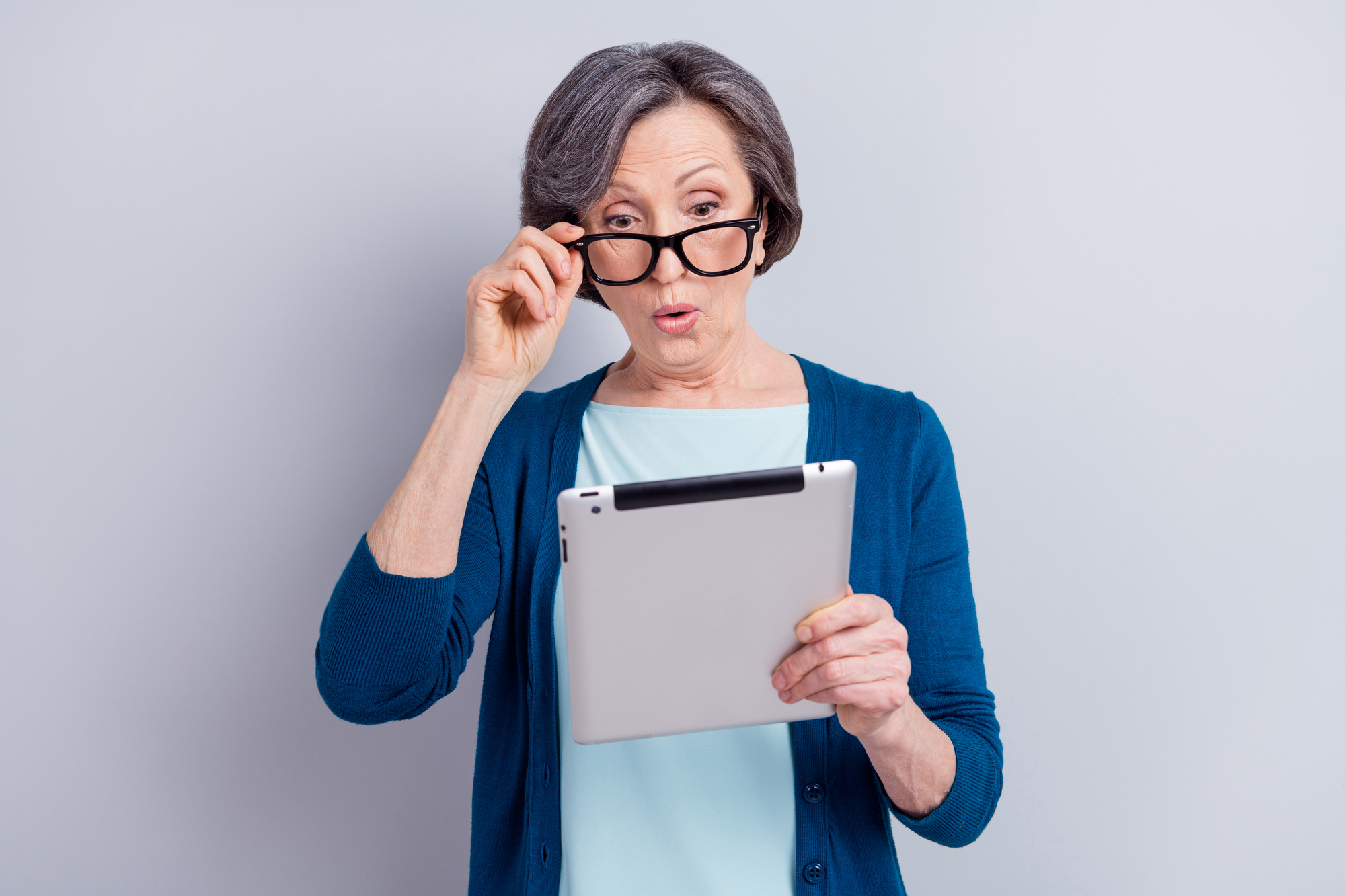 Senior woman reading online news on a tablet. The way information is presented in social media, emails or online news articles can make it very difficult to separate fact from fiction.