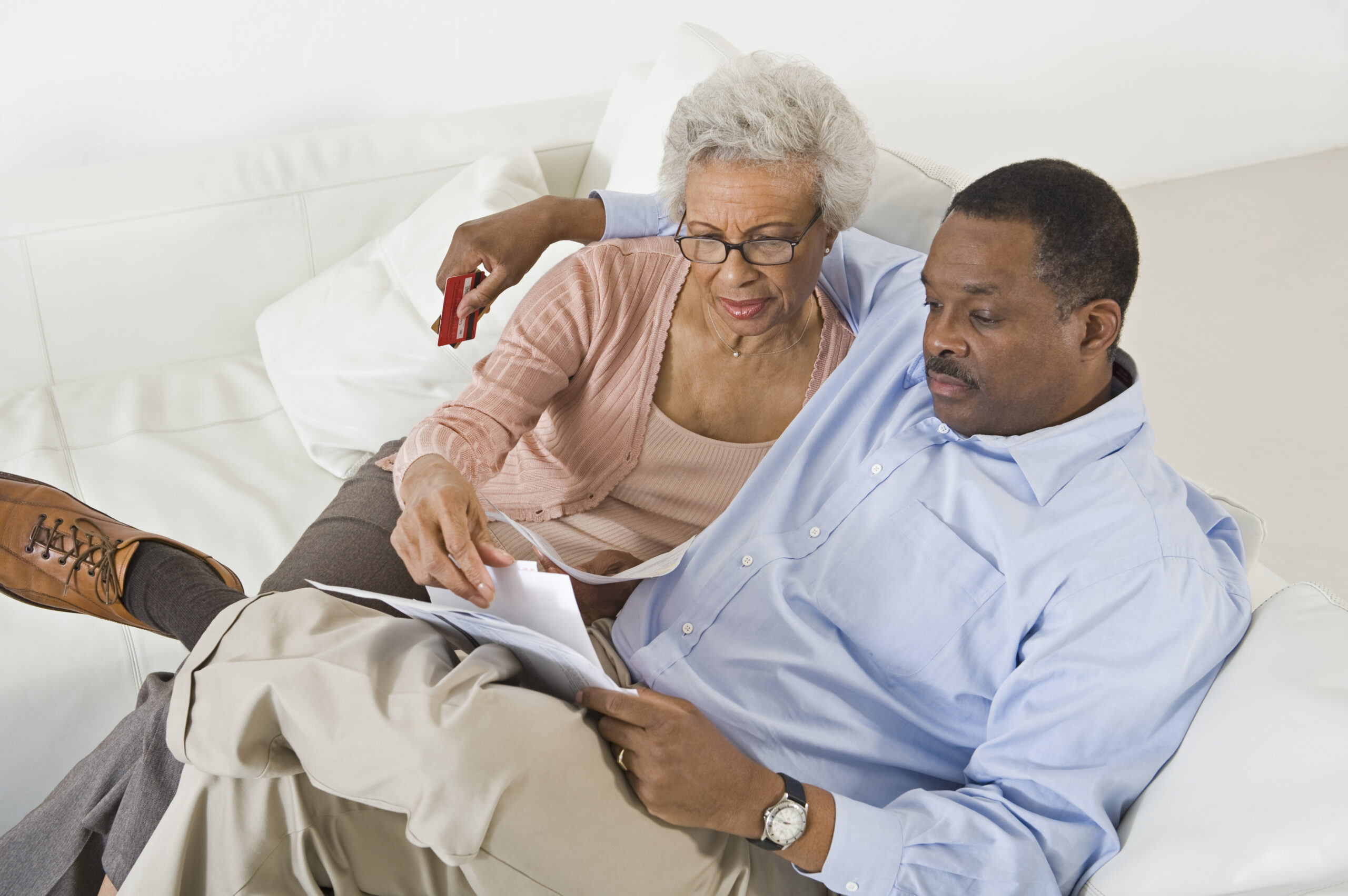 Senior couple sitting on couch calculating living expenses