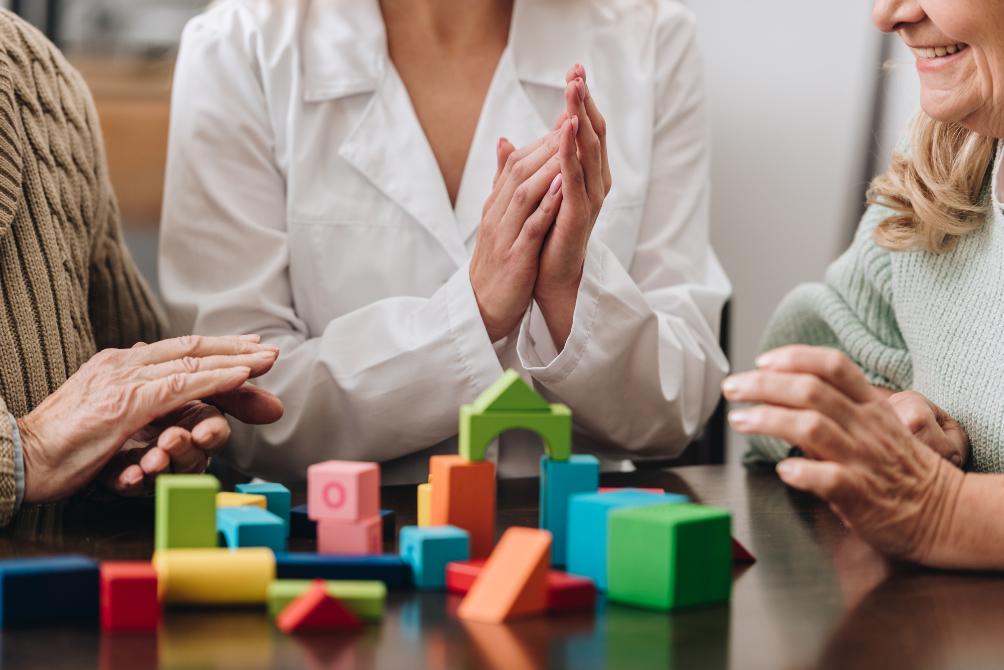 Image of memory care patients sitting at a table using blocks to do memory exercises.