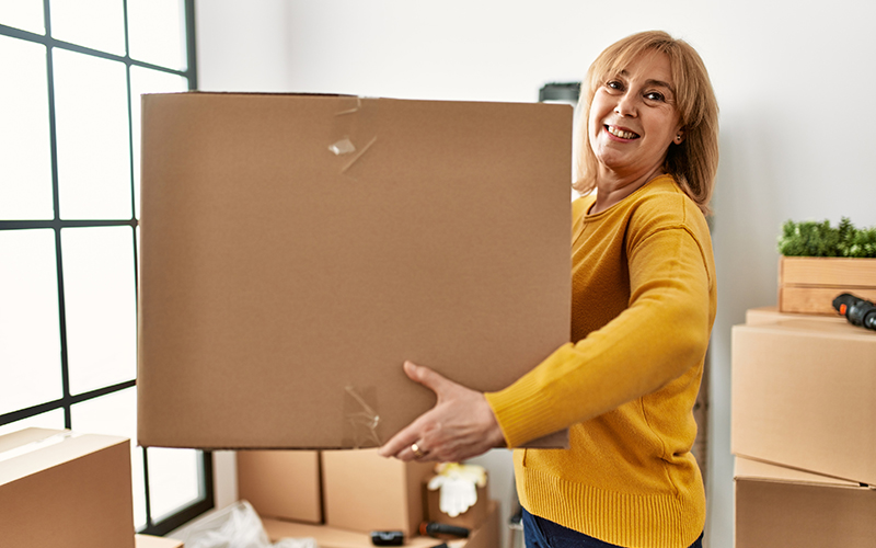 Adult daughter helping her senior parents move boxes