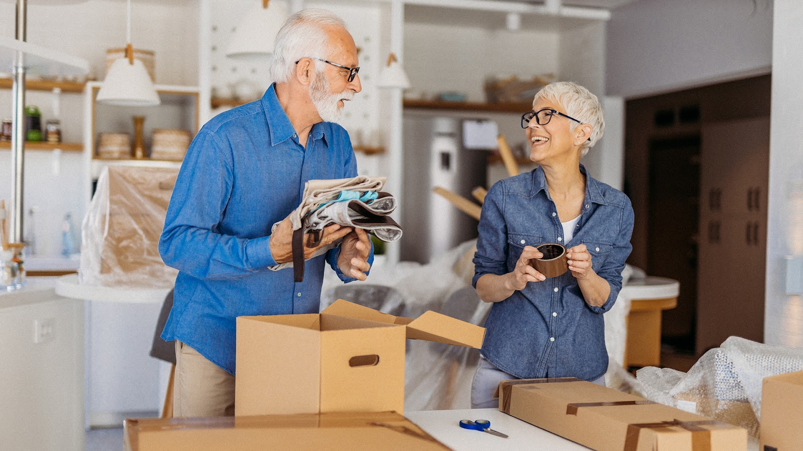 Senior couple packing personal items into moving boxes