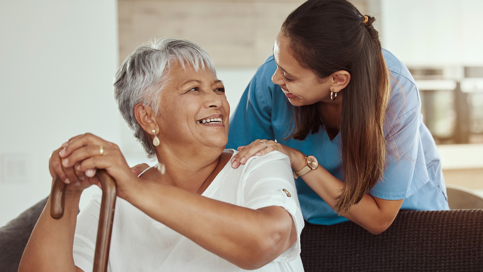 Senior woman with a cane sitting on a couch with her caregiver